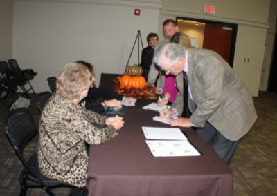 A woman signing papers at an event.