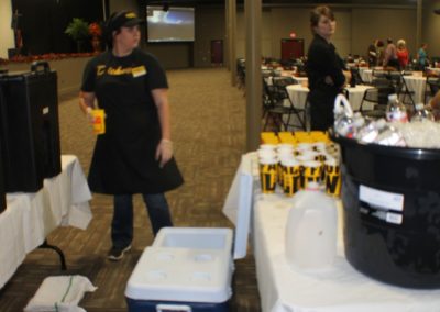 A woman standing next to tables with drinks on them.
