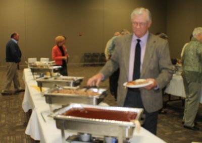 A man in suit and tie standing at a buffet line.