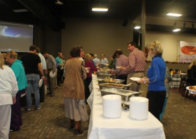 A group of people standing around a buffet line.