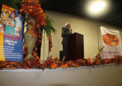 A man standing at the podium with leaves around him.