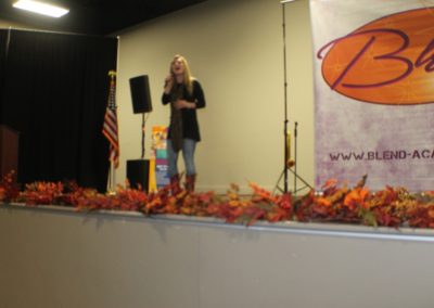 A woman standing on stage with leaves around her.