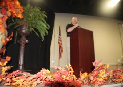 A man standing at the podium with leaves around him.