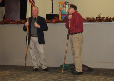 Two men standing next to each other holding poles.