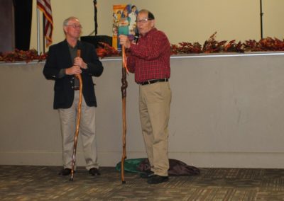 Two men standing next to each other holding a stick.