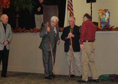 Two men standing next to each other holding walking sticks.