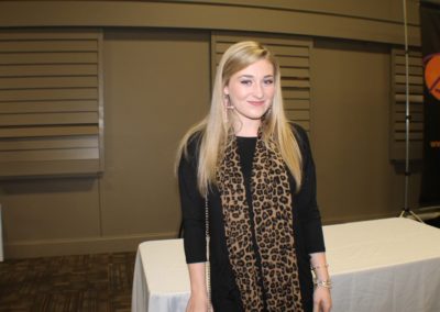 A woman standing in front of a table with a leopard print scarf.