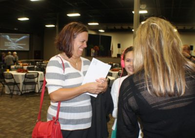 A woman is holding papers and talking to two other women.